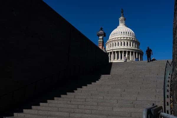 The U.S. Capitol building seen in the background. A U.S. Capitol Police officer walks down the stairs in the foreground.