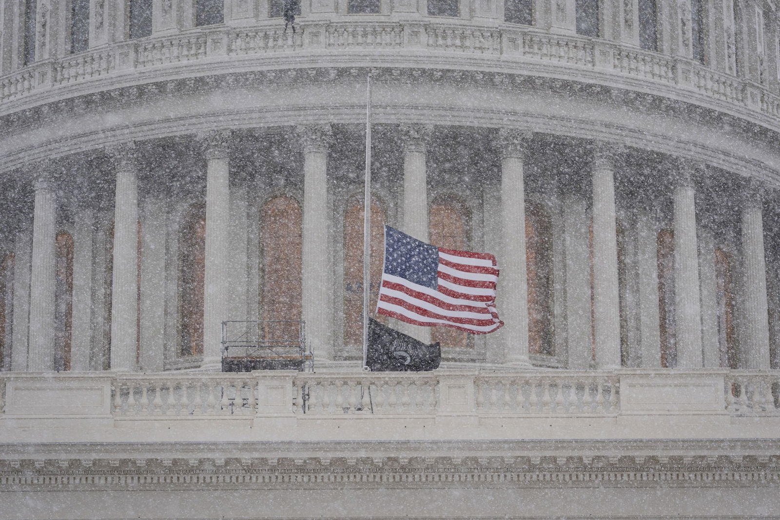 A view of a US flag on a pole outside the Capitol Building appears fuzzy from falling snow