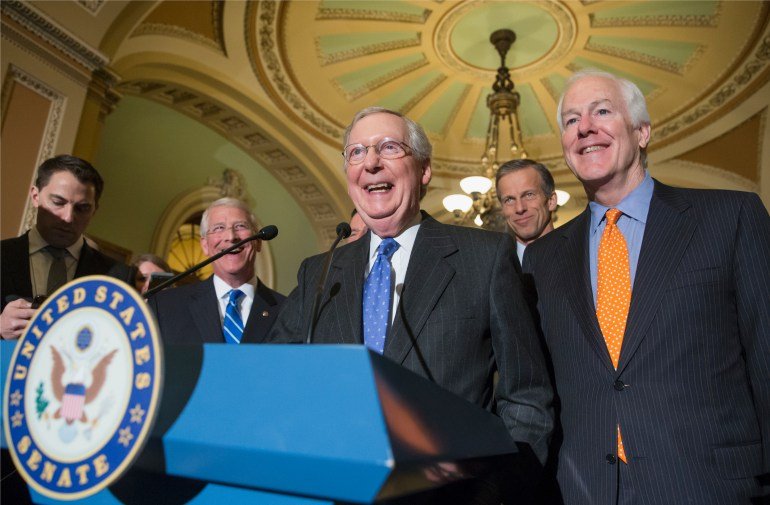 Mitch McConnnell stands behind a podium in 2016, surrounded by Congressional colleagues.